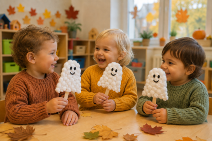 Drei Kinder halten gebastelte Gespenster aus Watte am Tisch.