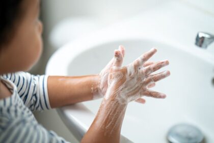 Kind seift sich die Hände an einem Waschbecken ein.